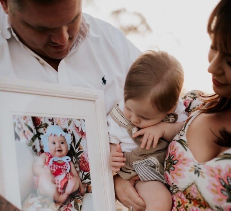 Tenille James Family photo holding photo of Andie 2