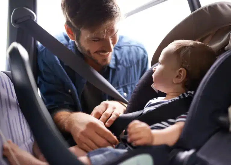 Dad putting baby in a car seat