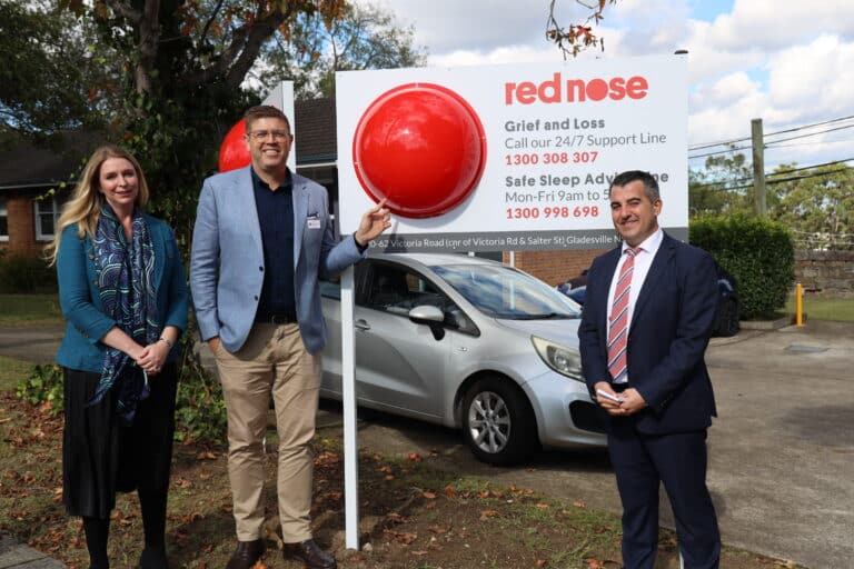 Federal Member for Federal Member for Bennelong, Jerome Laxale MP, Nick Xerakias, Board Chair of Red Nose Australia and Amy Cooper, CEO of Red Nose Australia, posing in front of Red Nose Australia's new Sydney office.