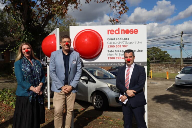 Federal Member for Federal Member for Bennelong, Jerome Laxale MP, Nick Xerakias, Board Chair of Red Nose Australia and Amy Cooper, CEO of Red Nose Australia, posing in front of Red Nose Australia's new Sydney office.