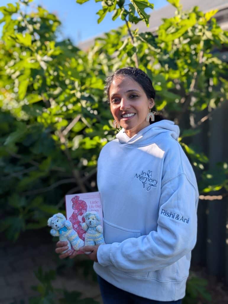 Swaathi holding a copy of Little Life, Big Loss in her garden