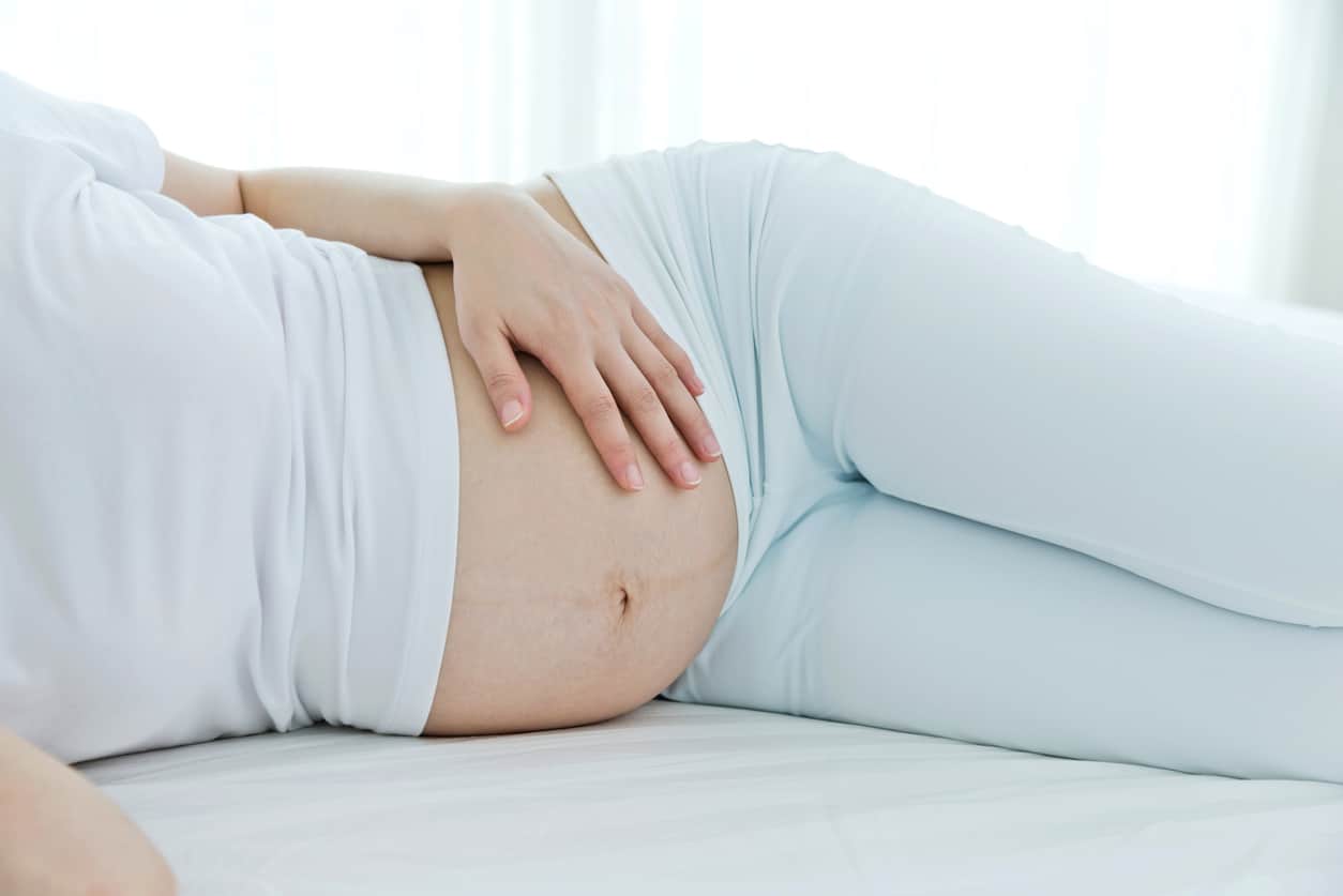 Pregnant woman resting on her side in bed, the safest position to go to sleep after 28 weeks