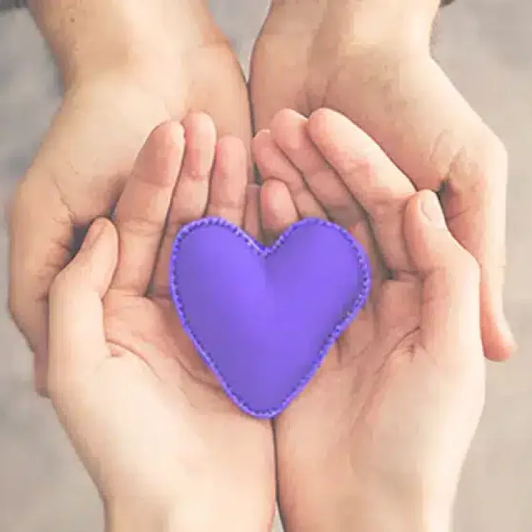 Two hands holding a purple heart.
