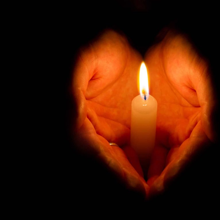 hands holding a burning candle