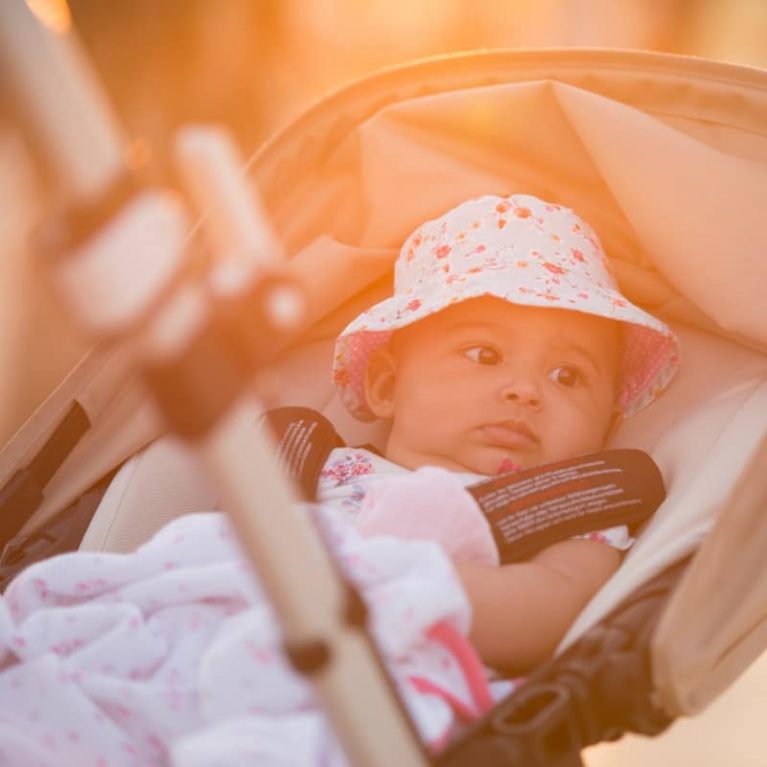 Baby in a pram wearing a hat